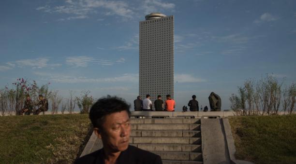En la foto, la  gente se sienta en un banco del río de Taedong antes del hotel de Yanggakdo en Pyongyang, en Corea del Norte. Foto: AFP