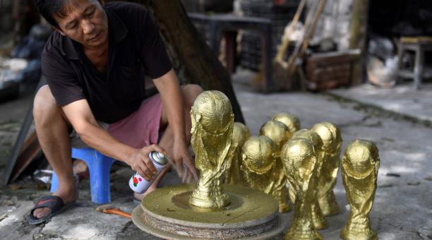 Esta foto tomada el 5 de junio de 2018 muestra al artesano vietnamita Vuong Hong Nhat pintando un modelo de yeso del trofeo de la Copa Mundial de fútbol en un taller en Hanoi. Foto: AFP