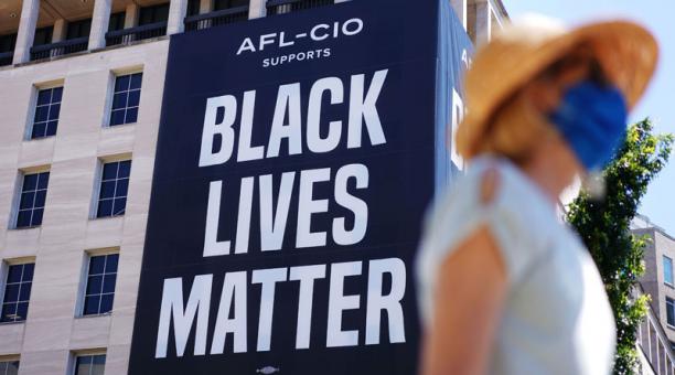 Una mujer camina debajo de una gigantografía con el lema 'Black Lives Matter', cerca de la Casa Blanca en Washington, DC, Estados unidos, el 12 de junio del 2020. Foto: AFP