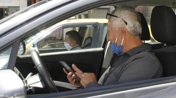 Un conductor emplea mal su mascarilla, aparte de que revisa su celular.