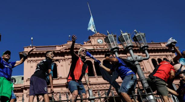 Hinchas subidos a una valla frente a la Casa Rosada, donde fue  el velorio. Foto: EFE