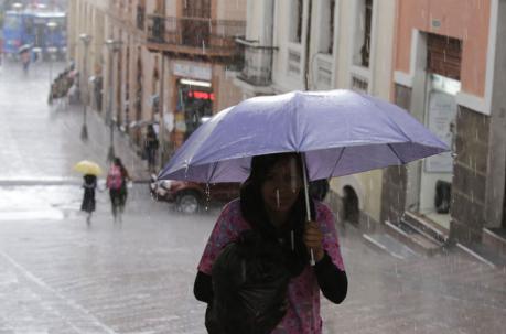 En la foto, una mujer se cubre de la lluvia con una paraguas. Foto: Alfredo Lagla / ÚN