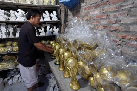 El artesano vietnamita Vuong Hong Nhat arregla modelos de yeso del trofeo de la Copa Mundial de fútbol en su taller. Foto: AFP
