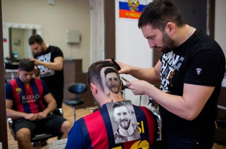 El peluquero serbio Mario Hvala crea un tatuaje de pelo que muestra el retrato del futbolista argentino Lionel Messi en la cabeza de un fanático. Foto: AFP