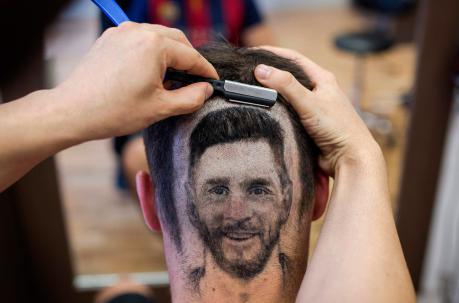 El peluquero serbio Mario Hvala crea un tatuaje de pelo que muestra el retrato del futbolista argentino Lionel Messi en la cabeza de un aficionado. Foto: AFP