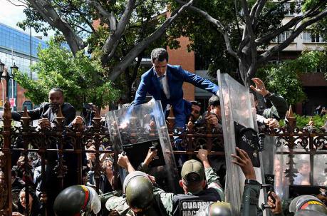Juan Guaidó intentaba saltar las verjas de la sede del Parlamento, bloqueado por uniformados con escudos antimotines. Foto: AFP